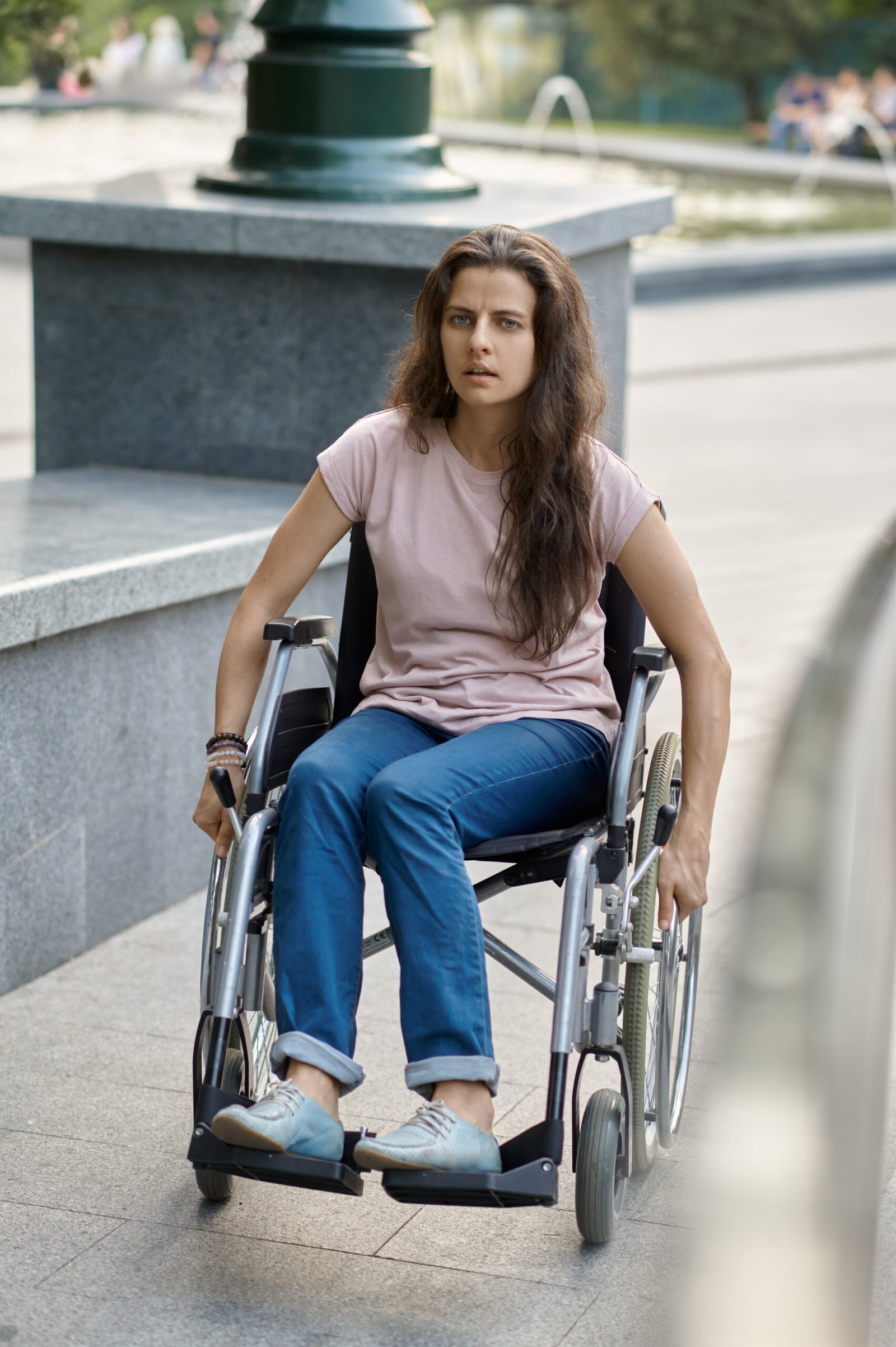 Disabled woman in wheelchair climbs the ramp. Paralyzed people and disability, handicap overcoming. Handicapped female person walking in park